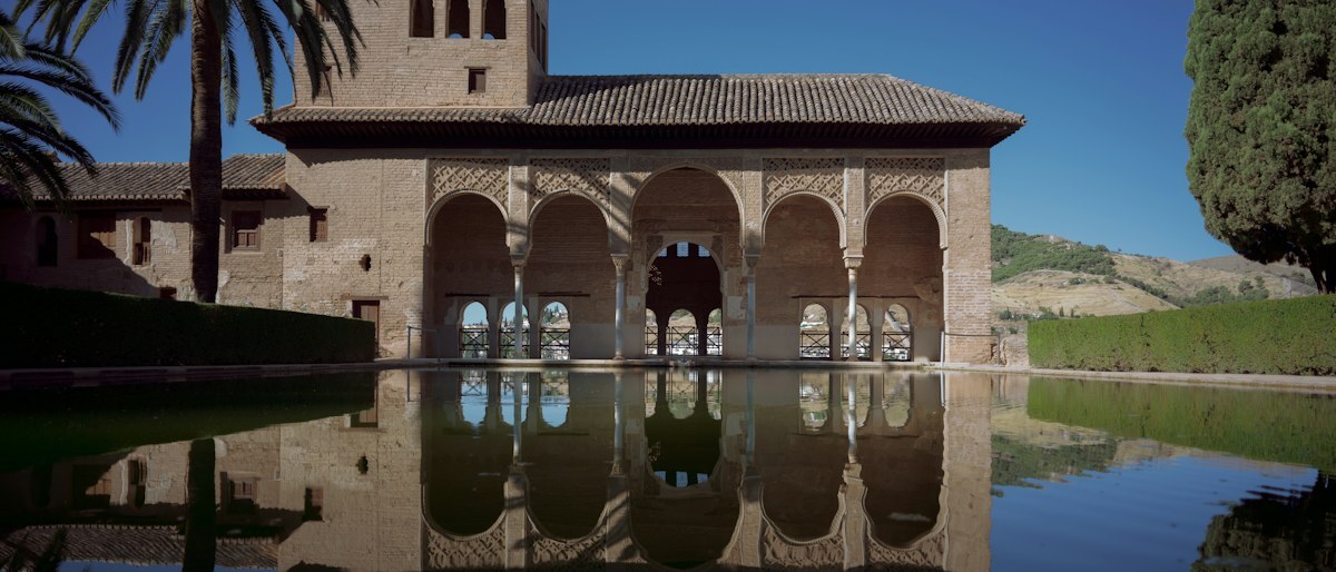 The arched Partal Palace of the Alhambra reflected in a still pool