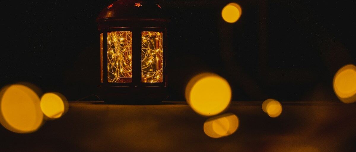Eine leuchtende Laterne im Dunkeln mit sanften Lichtpunkten dahinter