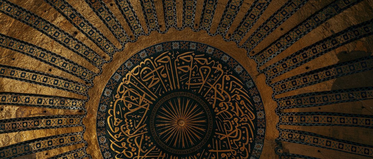 Gold Arabic calligraphy radiating across a circular ceiling