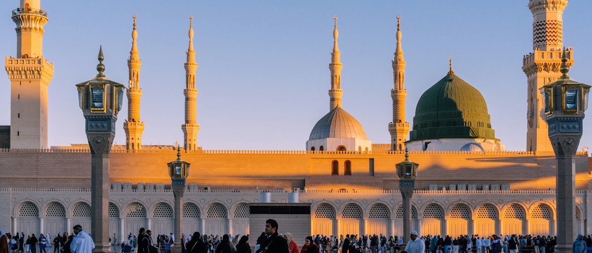Los minaretes y la cúpula verde de la Mezquita del Profeta en Medina bajo una luz cálida