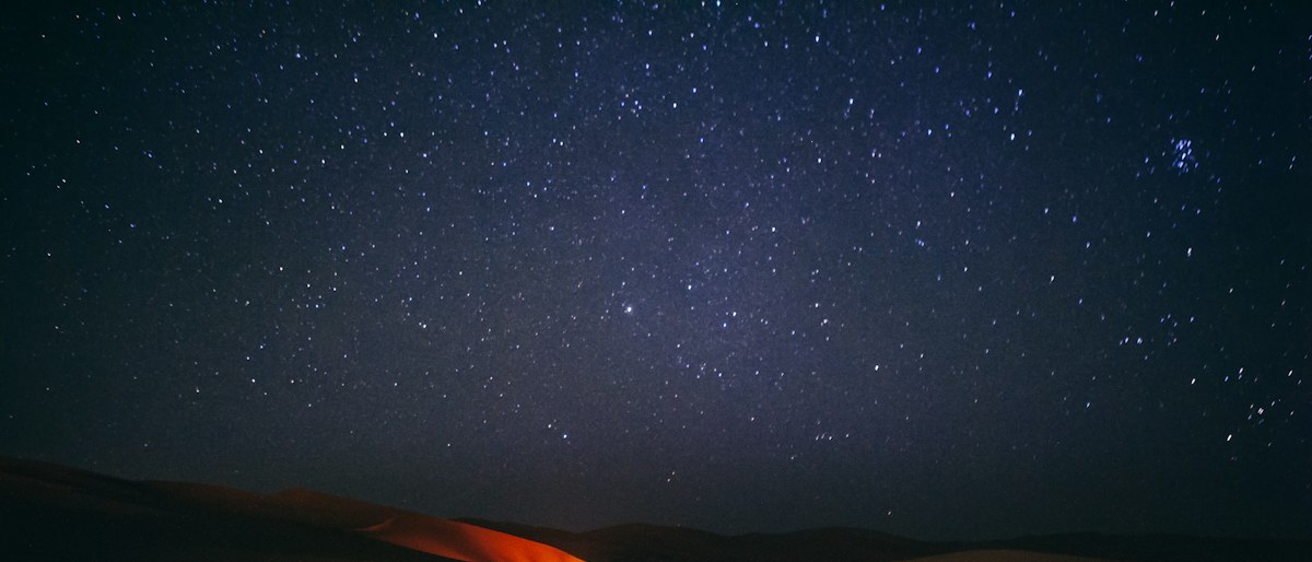 Une silhouette solitaire dans un désert, la nuit, sous un ciel rempli d’étoiles