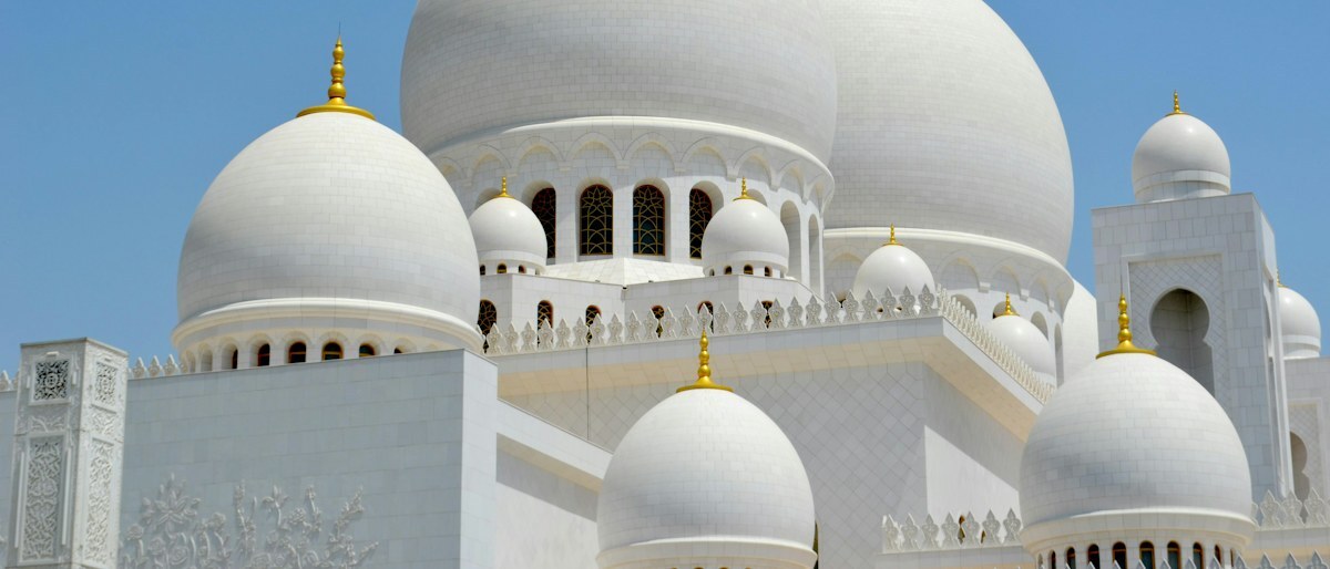 Le cupole bianche di una grande moschea sotto un cielo azzurro e limpido